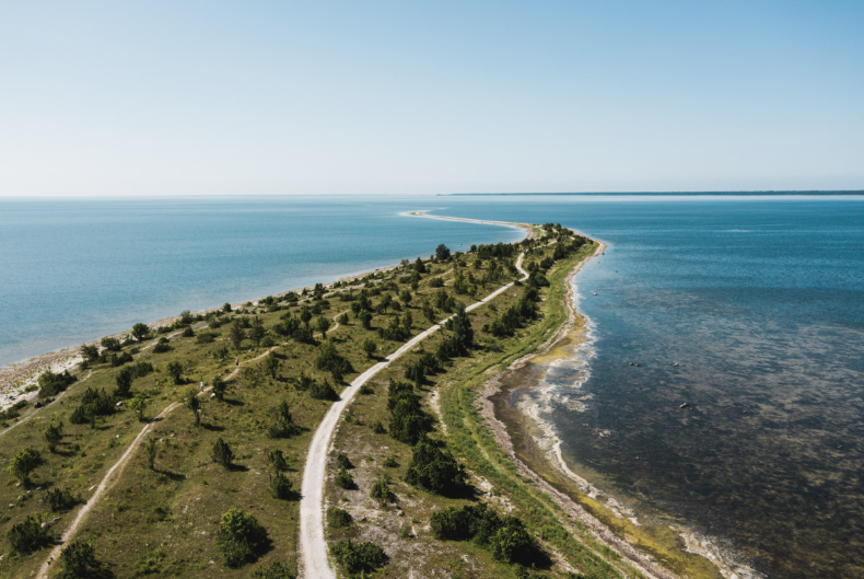 Aerial view of a narrow coastal peninsula in Estonia with a trail path running between the Baltic Sea and calm inland waters