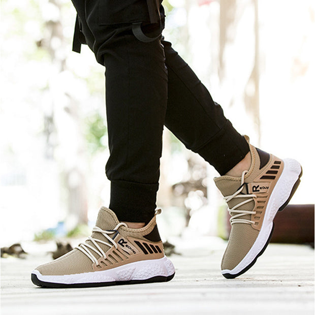 Beige mesh sports shoes with white soles in motion.