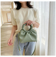 Woman holding green PU shoulder handbag in hallway