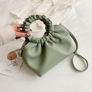 Green PU shoulder handbag with ruched handle on bed