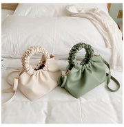 Cream and green PU bucket handbags on bed