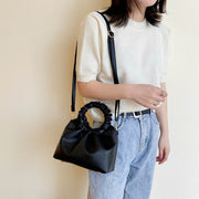 Woman wearing black PU shoulder handbag with ruched handle