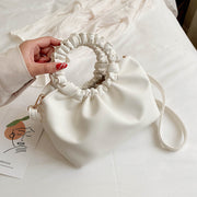 White PU shoulder handbag with ruched handle on bed