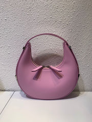 Pink crescent leather small bag against wall