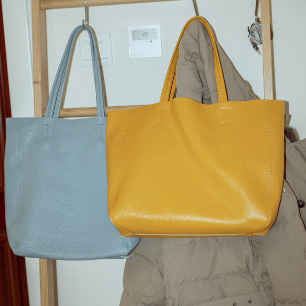 Yellow and blue leather tote bags hanging on a rack