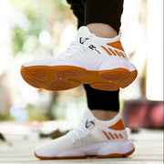 White sports shoes with orange accents being worn.