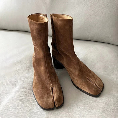 Brown suede split toe women's boots on a sofa