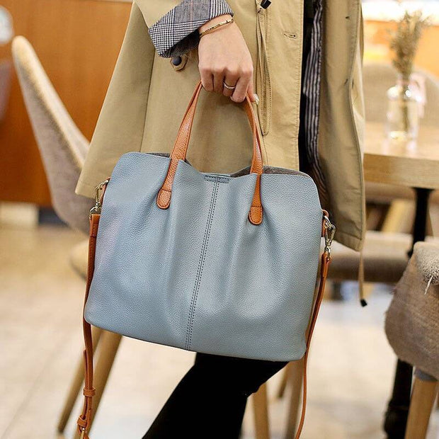 Person carrying blue leather tote bag in a cafe