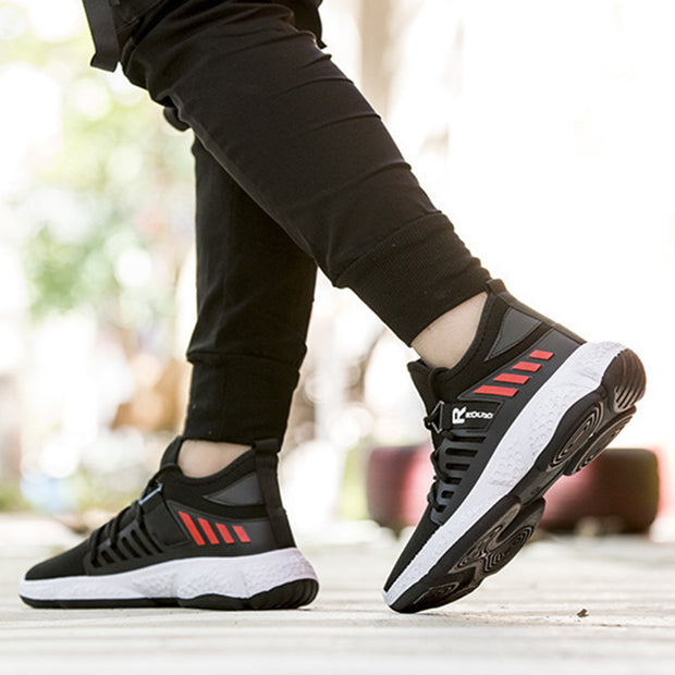 Black mesh sports shoes with red accents in action.