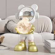 Gold space bear holding moon lamp on sofa