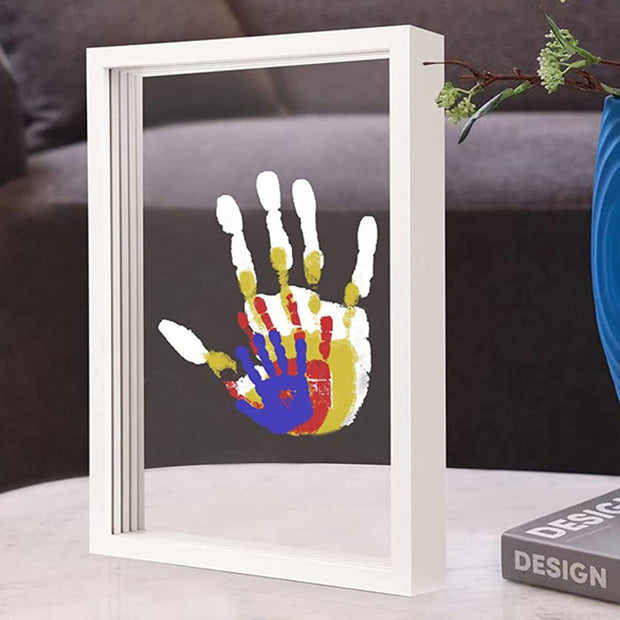 White DIY handprint frame with colorful prints on table