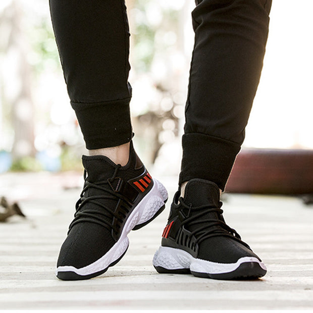 Black mesh sports shoes with red accents on feet.