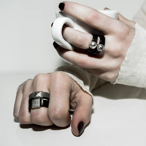 Close-up of hands wearing leather rings with silver details