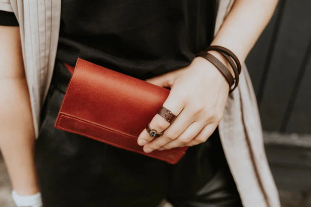 Person wearing leather band ring with red clutch