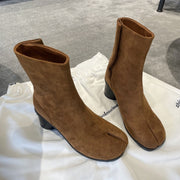 Brown suede split toe women's boots on white fabric