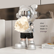 Silver astronaut bear with moon lamp on desk