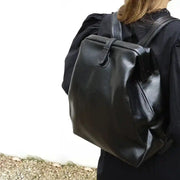 Black leather backpack worn by a person, showcasing its elegant and durable design, perfect for carrying essentials.